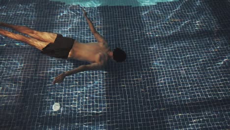 el hombre nada bajo el agua en la piscina