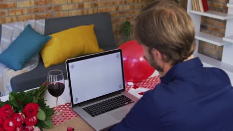 Rear-view-of-caucasian-man-waving-on-videocall-at-home