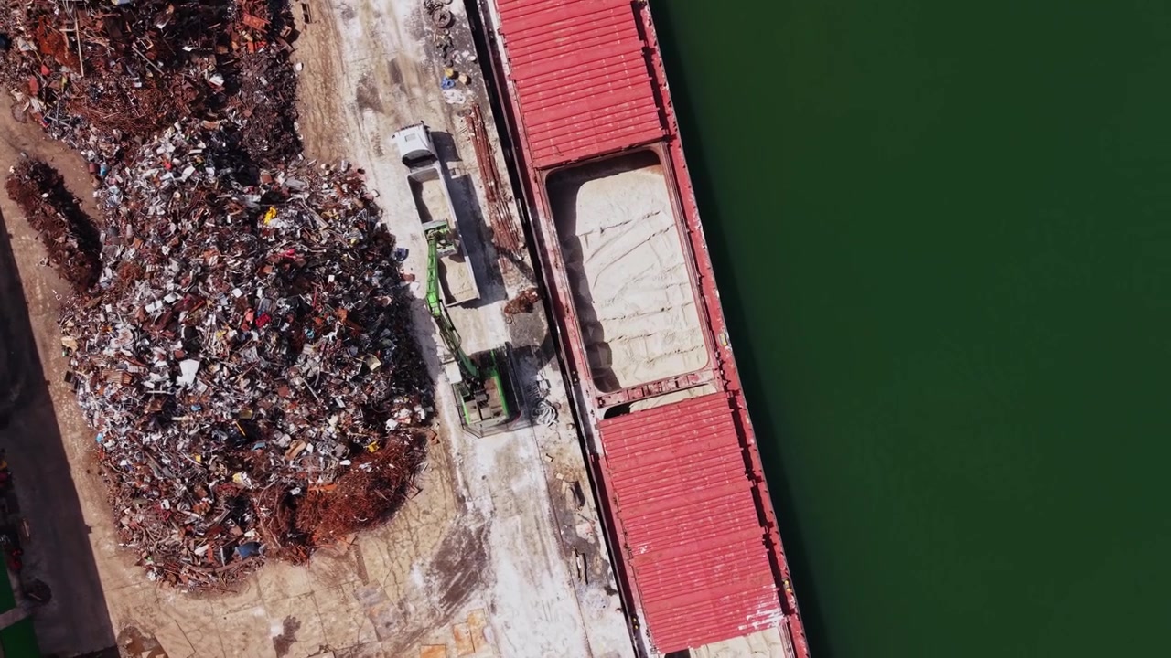 Processo di riciclaggio in un impianto di gestione dei rifiuti vicino a uno specchio d'acqua.