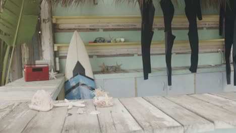 surfboards and hanging wetsuits in surf rental beach shack, slow motion