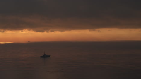 一艘皇家海军战舰在日出时在平静的海上航行