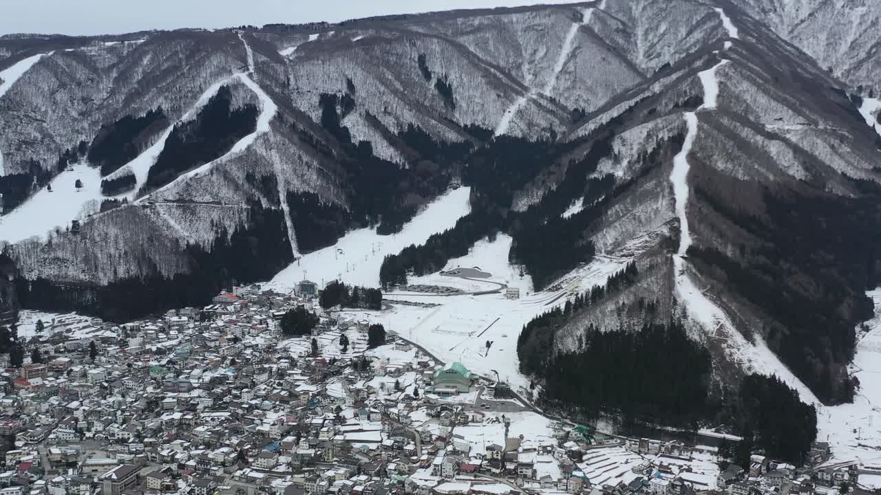 겨울에 산악 스키 리조트 아래 작은 마을을 공중 패닝