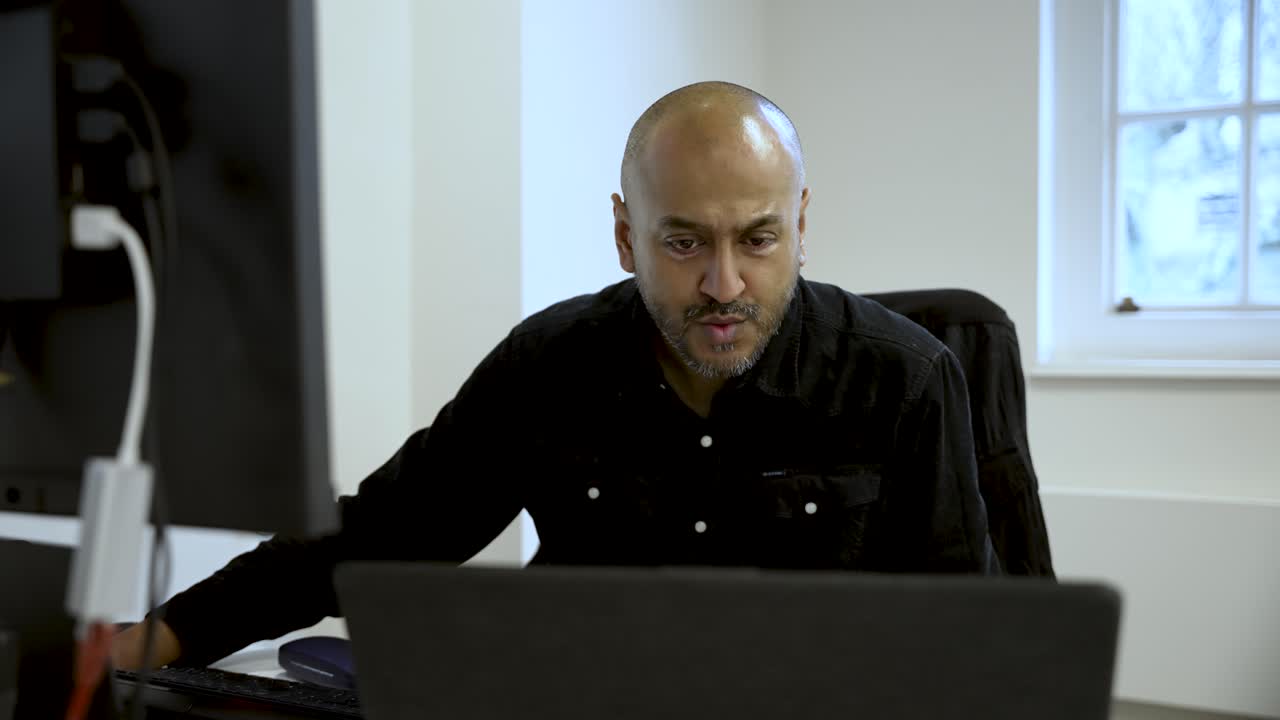 Professional office worker concentrating on tasks at a computer in a modern workspace.