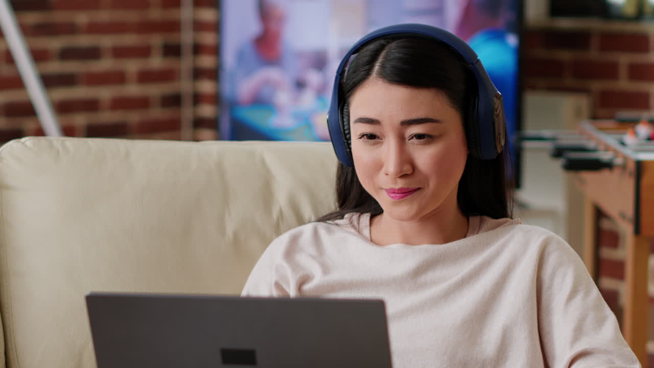 Woman using laptop with headphones at home