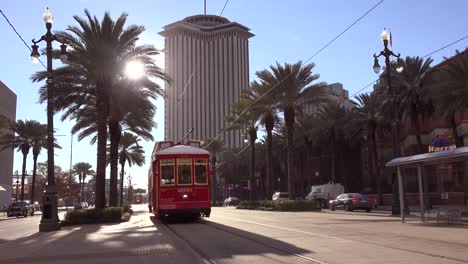 a red new orleans streetcar travels through the city