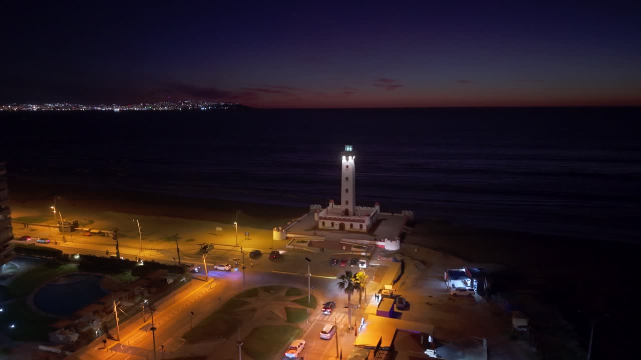 Evening view of Faro de La Serena, streets glowing with lights against a dark coastal horizon
