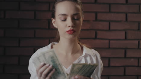serious woman counting money banknotes on brick wall. wealthy businesswoman