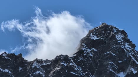 una vista de cerca de un majestuoso pico del himalaya como una nube blanca se rompe dramáticamente, revelando la cumbre y mostrando las fuerzas dinámicas de la naturaleza a gran altitud