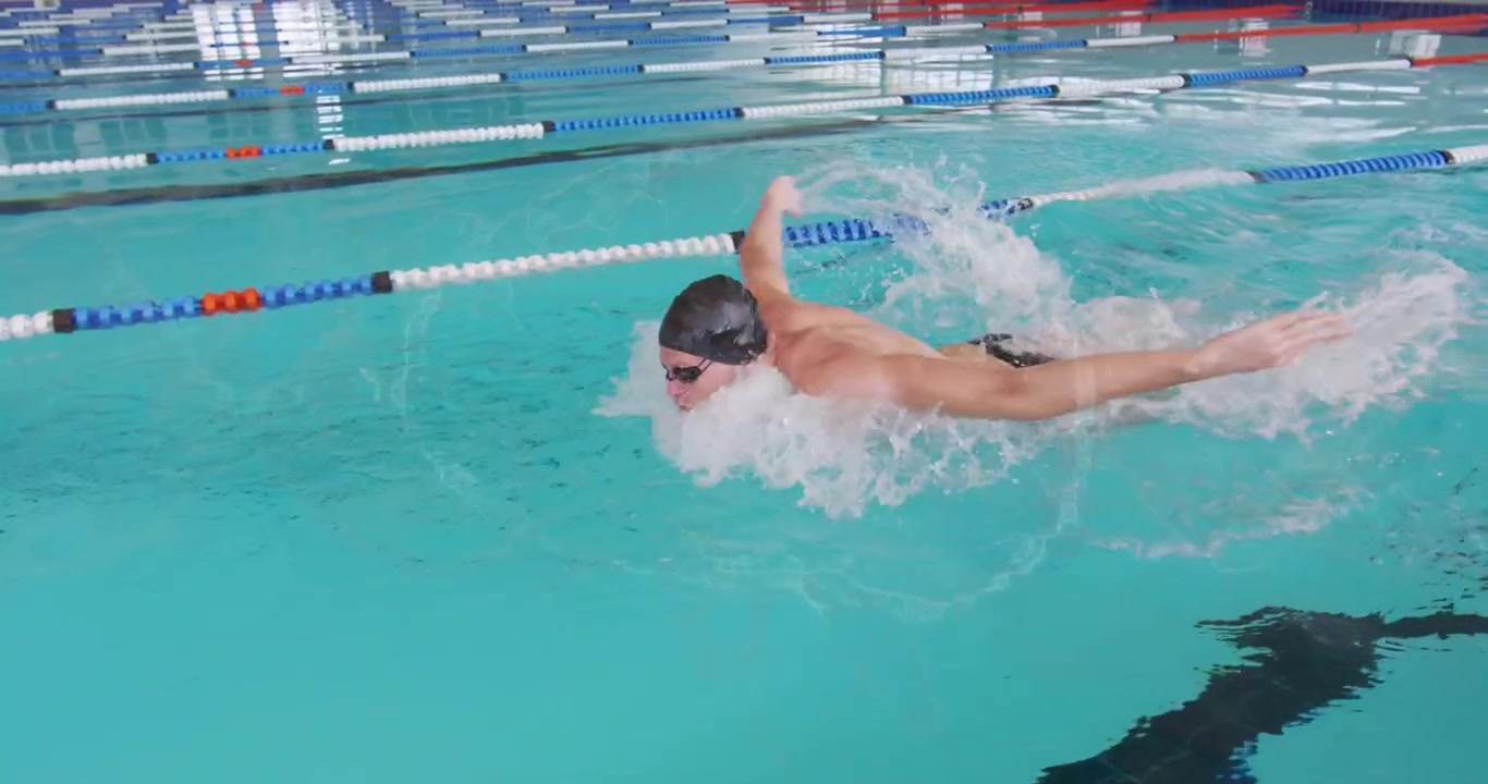 male swimmer gliding under lane rope lifting arms inhaling performing butterfly stroke for fitness