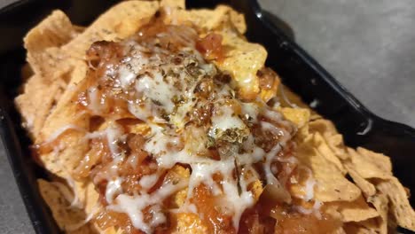 un recipiente de nachos con salsa de queso