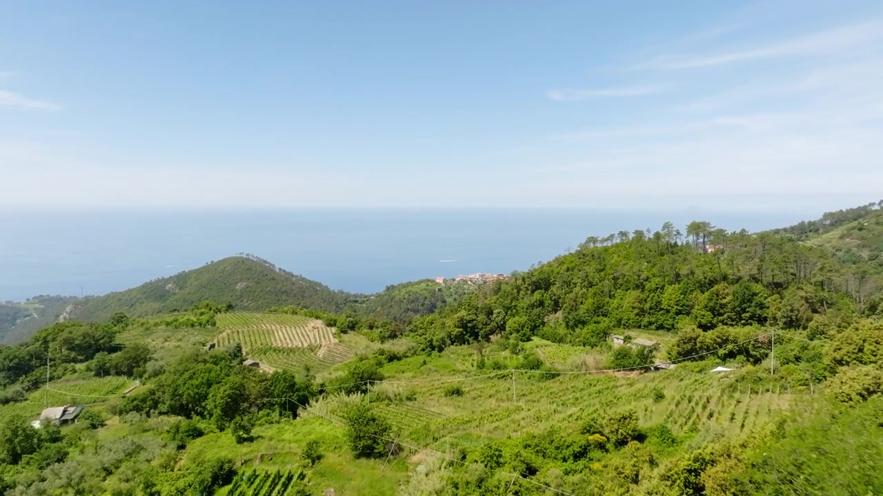 Terbang lintas drone udara di atas pegunungan hijau Bonassola di Liguria, Italia pada siang hari.
