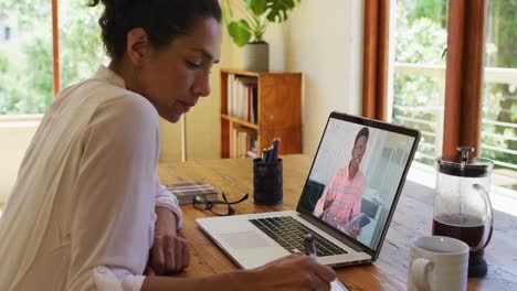 Afroamerikanische-Frau-Macht-Sich-Notizen,-Während-Sie-Zu-Hause-Einen-Videoanruf-Auf-Dem-Laptop-Führt