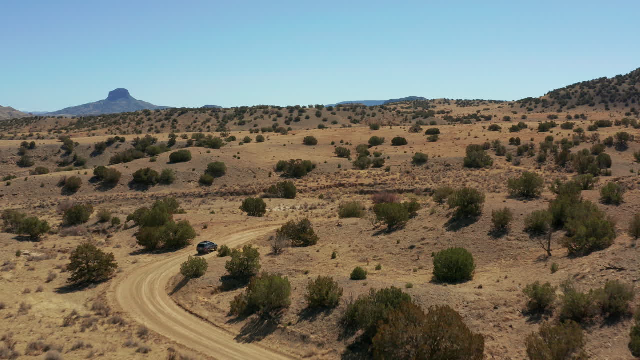 antena siguiendo el coche por un camino de tierra con curvas en un paisaje desértico