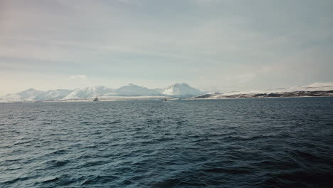 Cinematic-Wide-Static-Shot-of-Boat-Cruise-Sailing-along-the-Arctic-Fjords-in-Norway