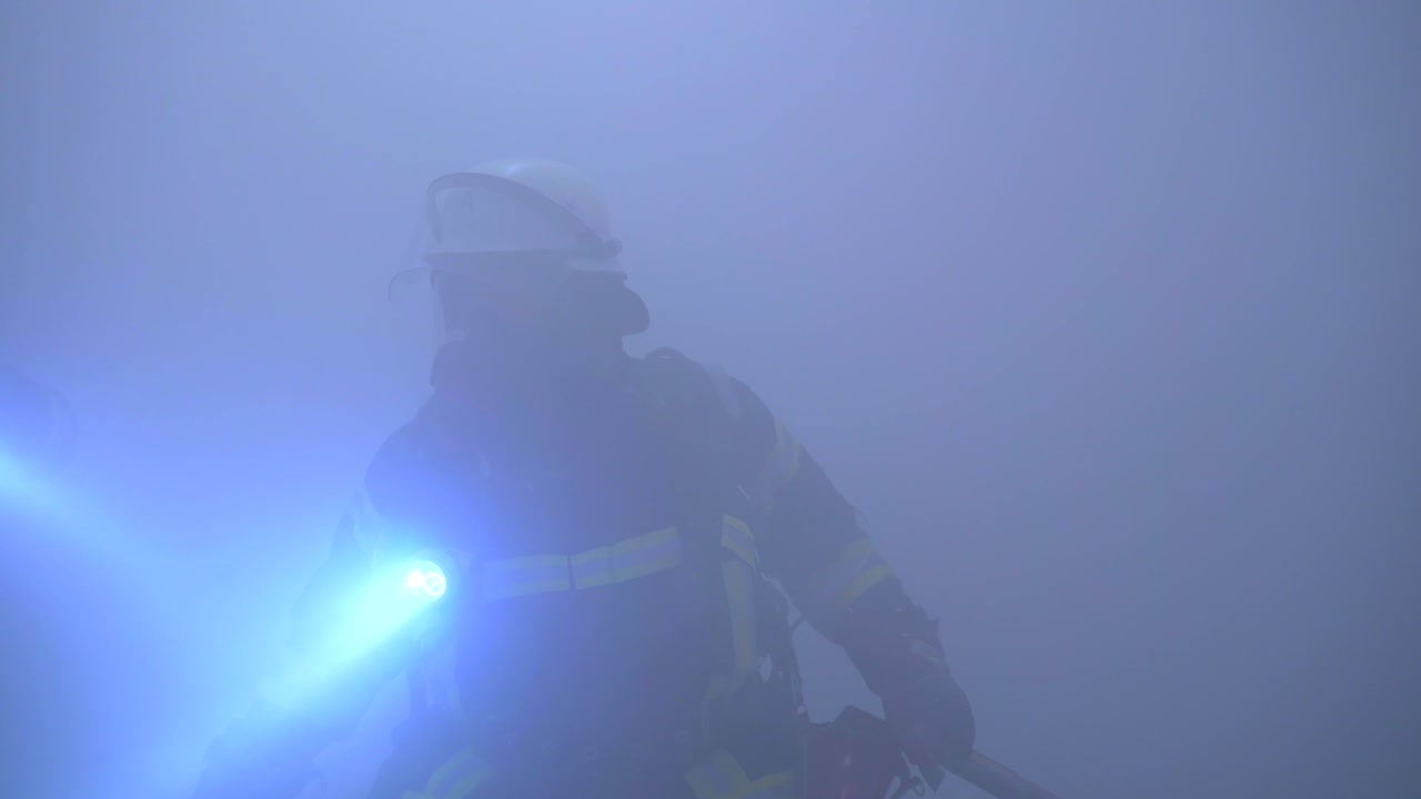 Fireman with flashlight and respirator in complete haze