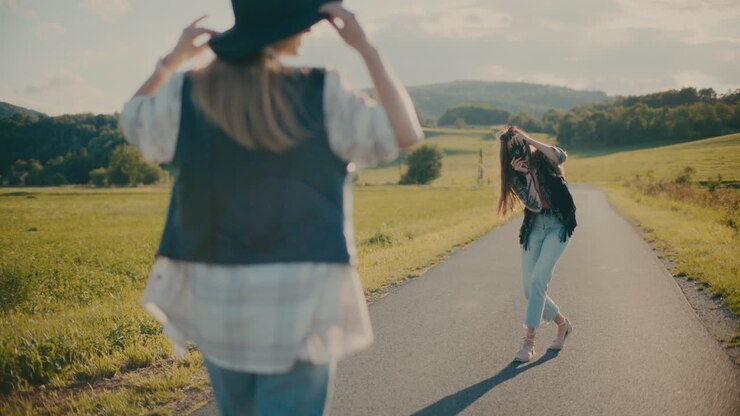 Woman Photographing Female Friend Posing With Hat