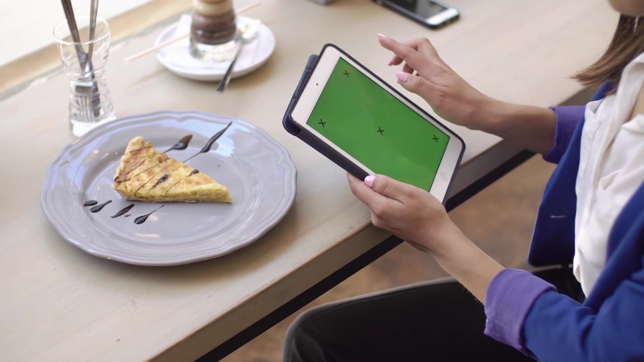 Kvinde stryger og trykker på tablet med grøn skærm på café