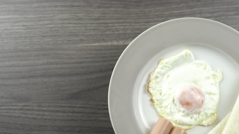 close up top view shot rotating.breakfast on a white plate on the right corner of the wooden floor
