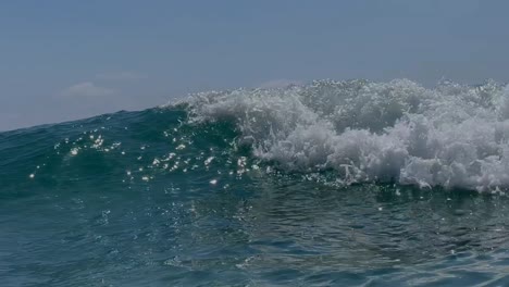 cresta de olas y rompiendo sobre la cámara con el sol brillando, en la cámara sur