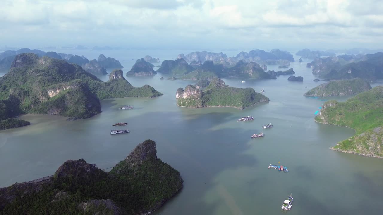 Semi orbit drone movement around limestone islets and tour boats on a sunny day in Cat Ba