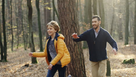 caucasian happy father with his little son running and playing in the forest