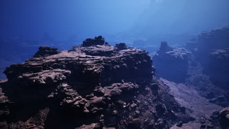 a dramatic landscape of a canyon with rocky cliffs and mountain range in the distance.