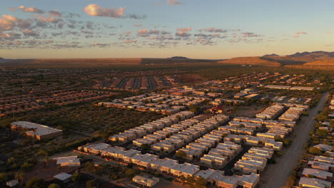 Mine-pilings-behind-town-of-Green-Valley-in-Arizona-during-sunrise-with-pretty-clouds,-drone-backwards