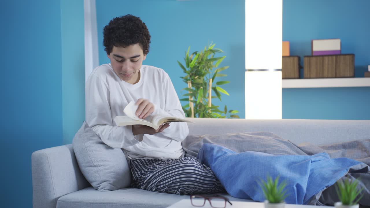Anak laki-laki membaca buku di sofa