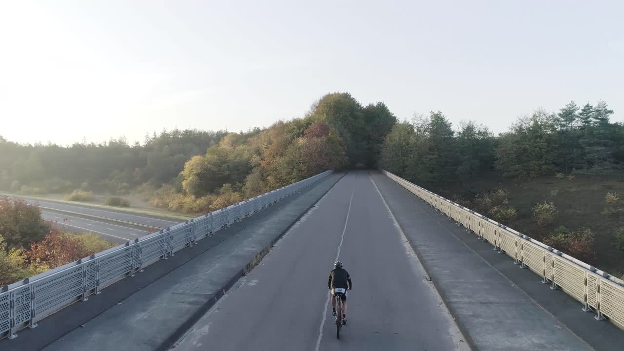一架山地自行车在高架桥上骑行后面的无人机镜头