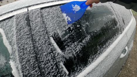 cleaning the side car windows of snow with ice scraper before the trip