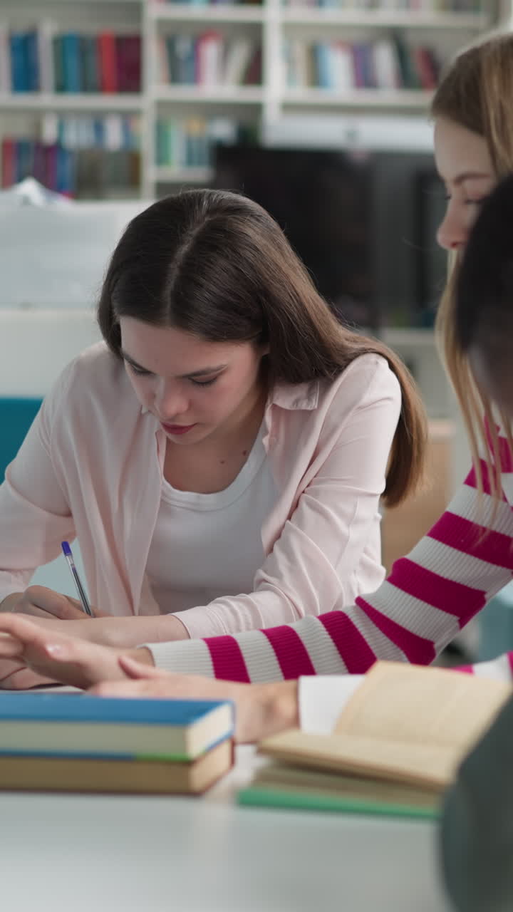 los estudiantes trabajan según la presentación en la biblioteca. los colegas escriben y navegan por internet mientras leen libros en la sala pública. diferentes fuentes y técnicas de educación para el trabajo de posgrado