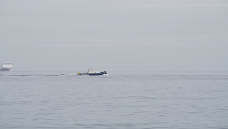 a small fishing vessel sailing off in front of a big passenger ship