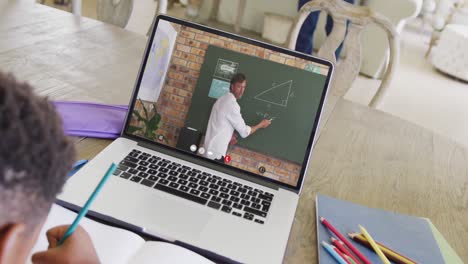 Diverse-male-student-having-class-during-laptop-video-call-with-male-teacher-in-slow-motion