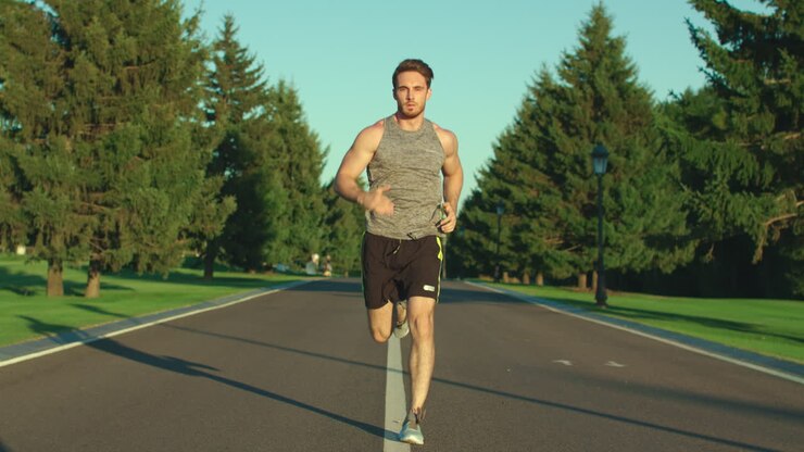 Sport man running on park road at summer