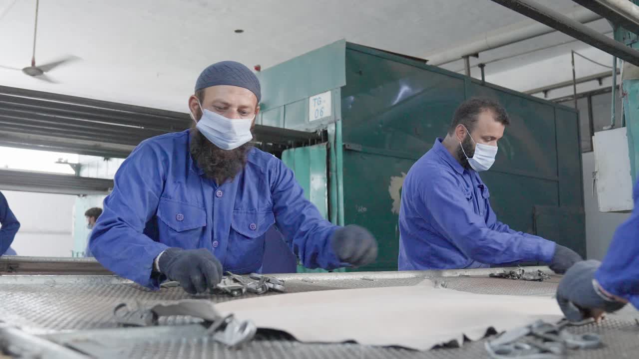 Leather factory workers stretching leather process drying frame in Islamabad Pakistan