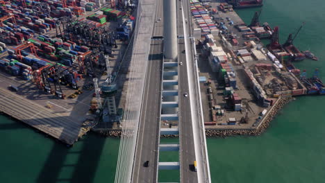 suspenseful shot of traffic on the wide stonecutters suspension bridge near the terminals of the hong kong container port