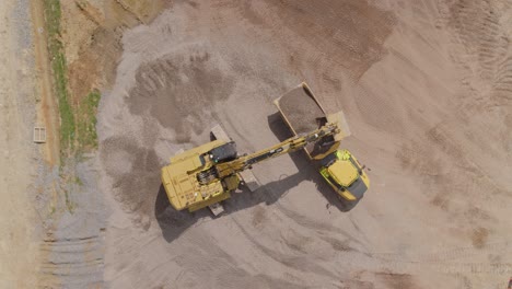 Ein-Bagger-Lädt-Auf-Einer-Großen-Baustelle-Kies-In-Einen-Muldenkipper