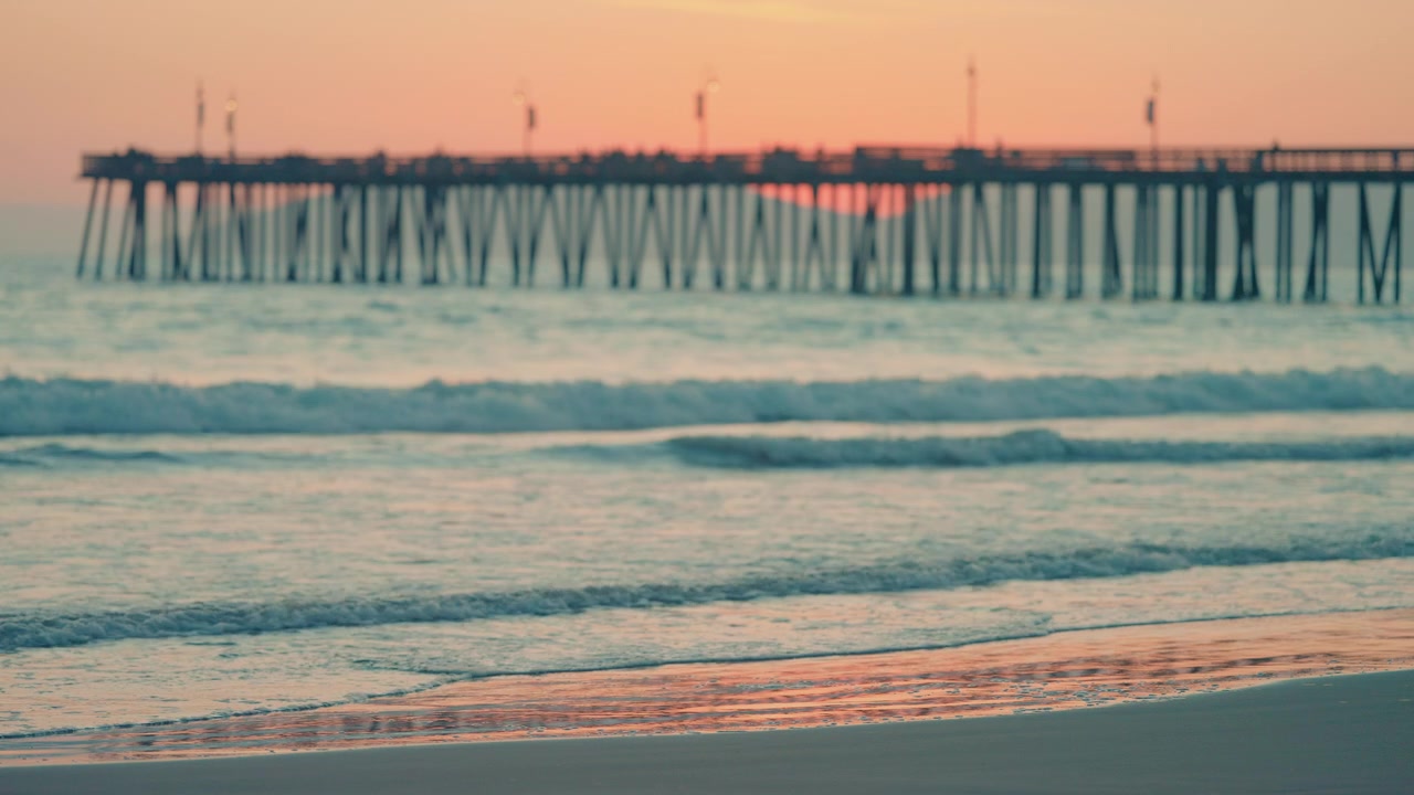 Bellissima spiaggia e molo della California che risplendono nella calda luce serale