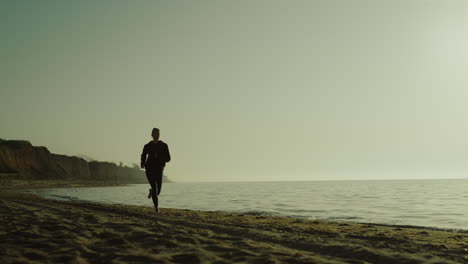 Sportlerin-Sprintet-Im-Freien-Bei-Sonnenaufgang.-Frau-Läuft-Am-Strand-In-Sportbekleidung.