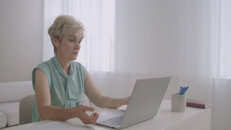 aged female teacher is lecturing online looking at web camera of laptop distant education by internet portrait of woman