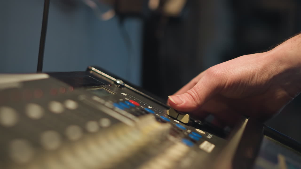 Close-up shot of a man adjusting equipment on a control panel with a focus on his hand. Soft light illuminates workspace, showcasing hands-on operation of technical equipment, precise control
