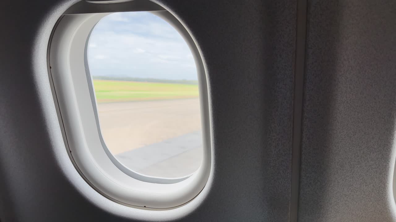 Airplane taxiing on runway, viewed from business class window, natural daylight, steady camera
