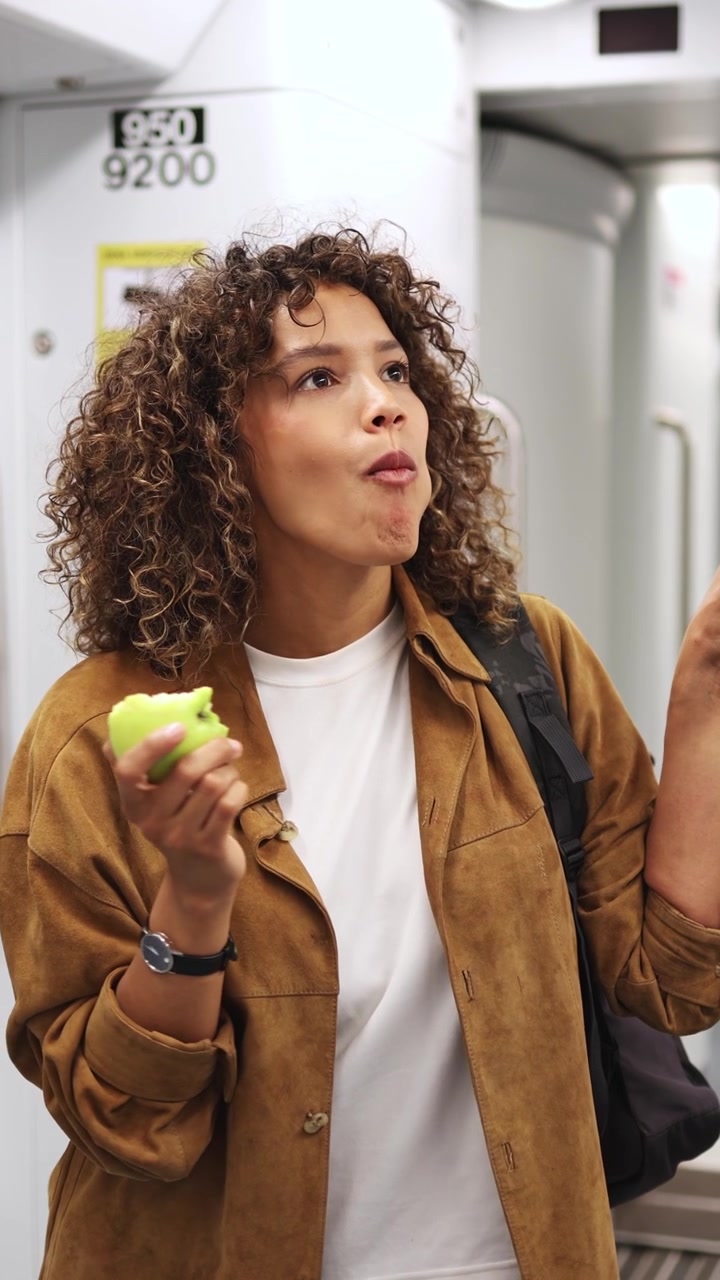 Young Woman Eating a Green Apple While Commuting on a Subway