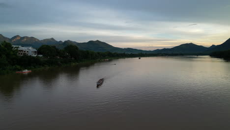 boats move about the mekong river at sunset in luang prabang