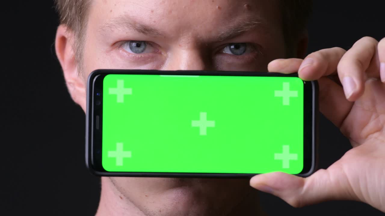 hombre sosteniendo un teléfono móvil con pantalla verde de clave de croma