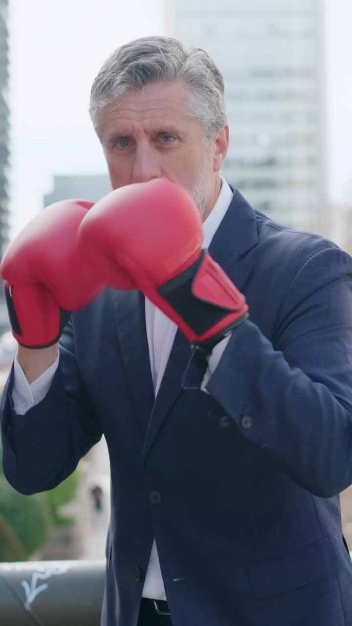 Uomo maturo in abito e guantoni da boxe rossi