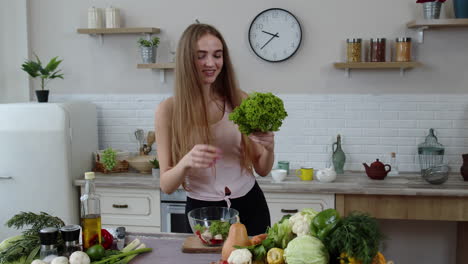 happy girl dancing, having fun and cooking salad with raw vegetables. throwing pieces of lettuce