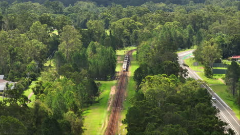 queensland train railway traveling through rural countryside suburb, 4k drone telephoto australia