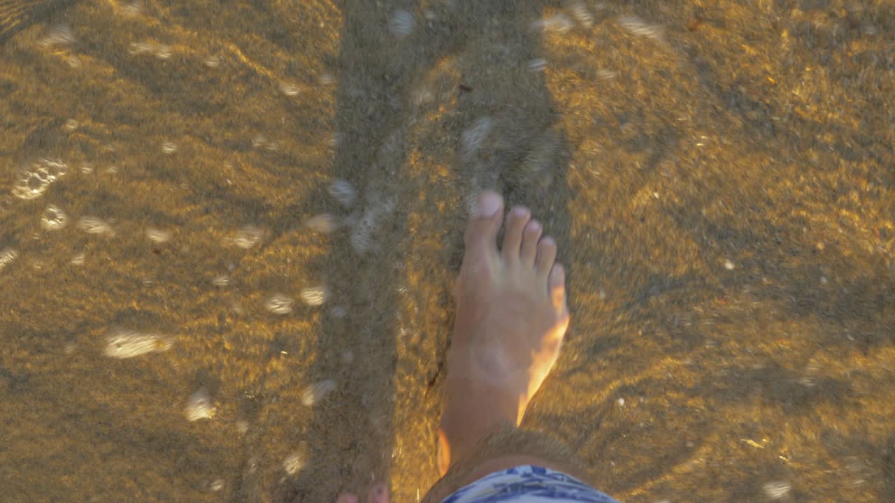 Barefoot vacationer walking in shallow sea water