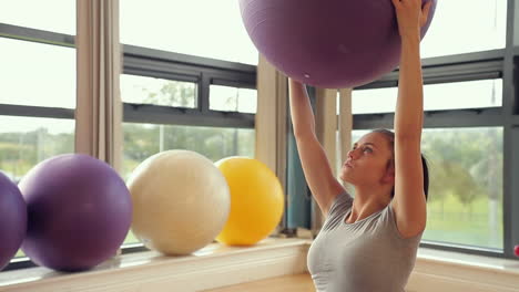 Sportliche-Brünette-Frau-Heben-Gymnastikball